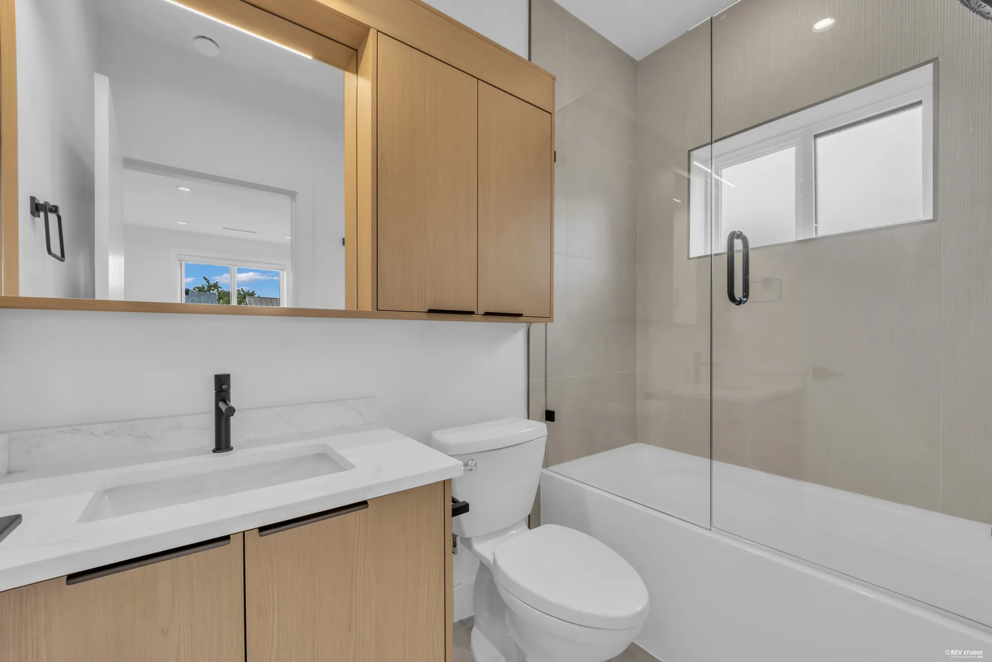 Bathroom with a tub, stone counter and a timber mirror cabinet