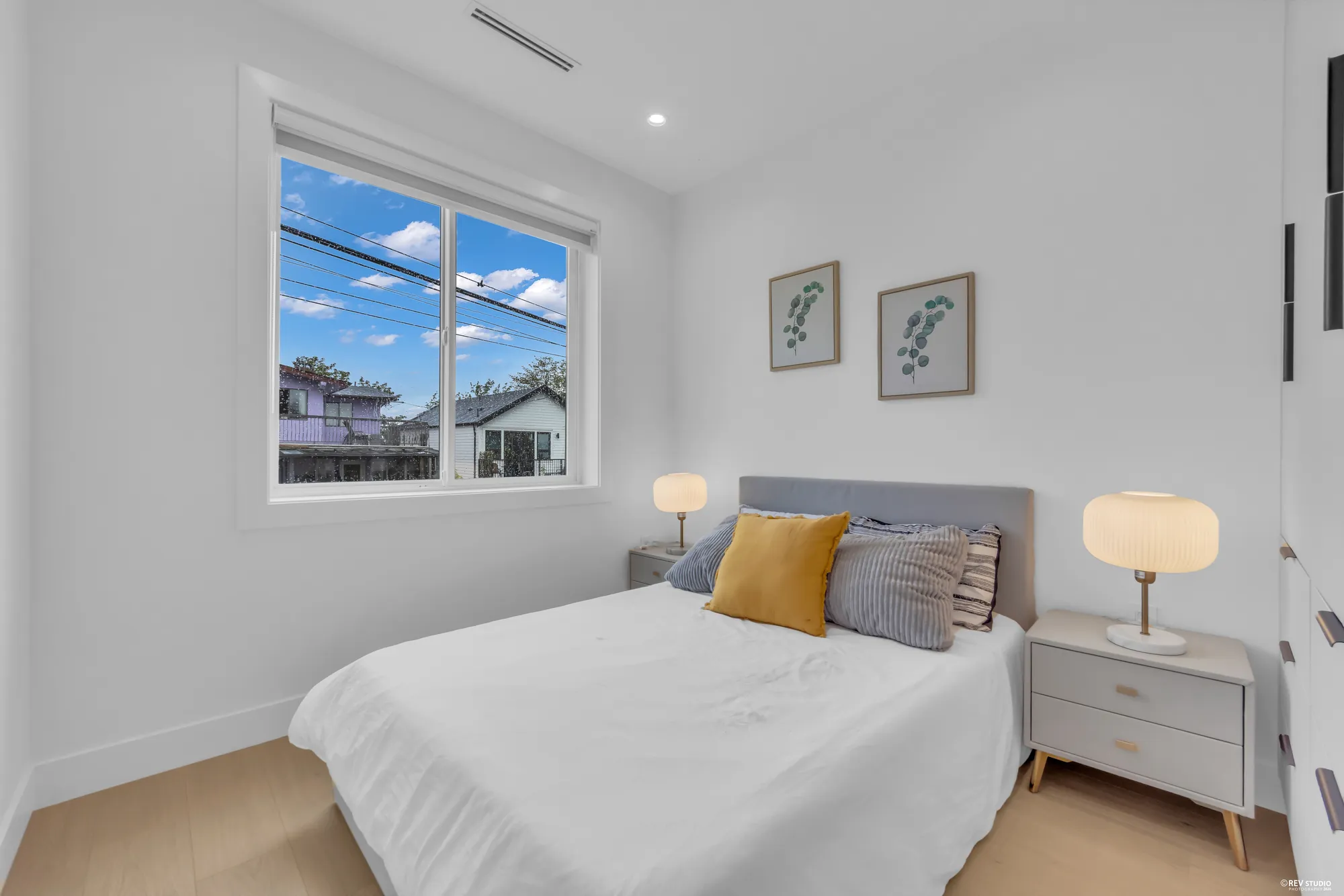 Second bedroom with a bed, a mustard cushion and two bedside lamps under a window