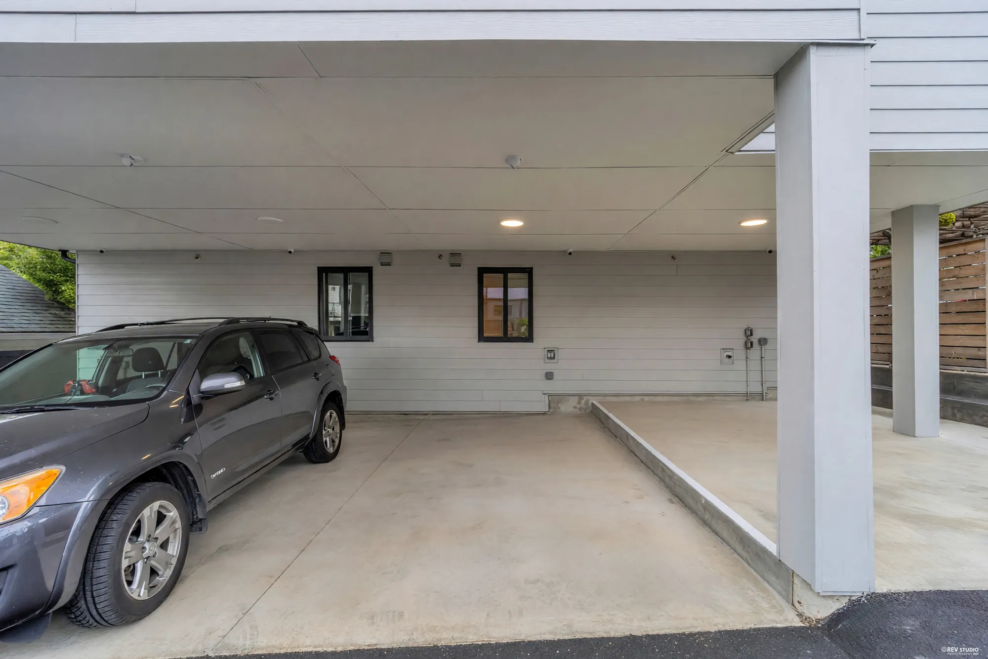 Inside the covered carport with a car parked and a door into the building