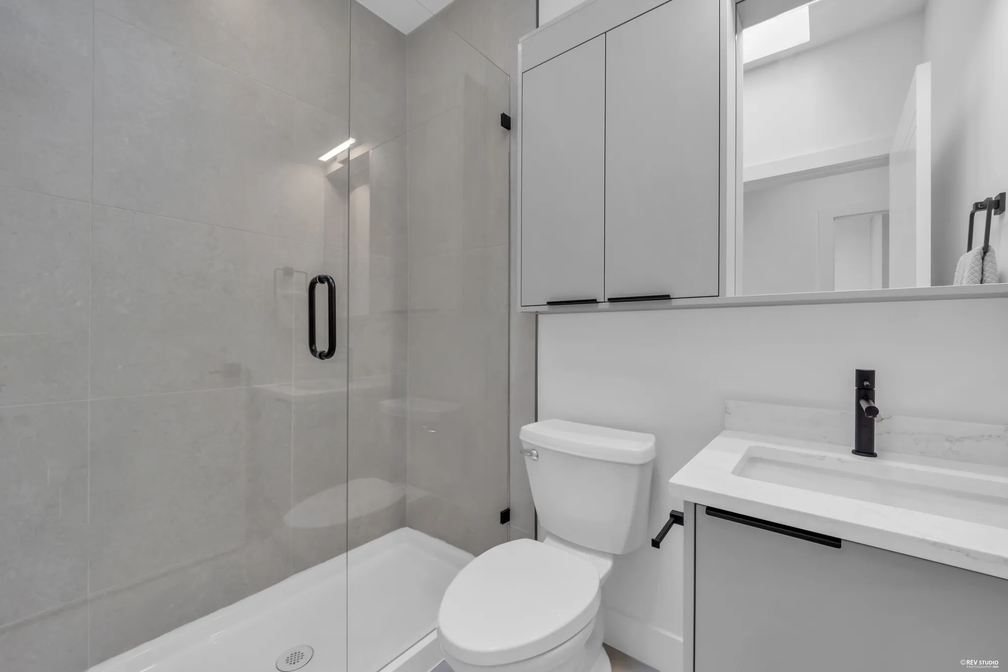 Ensuite with a glass shower, stone counter and a slim window