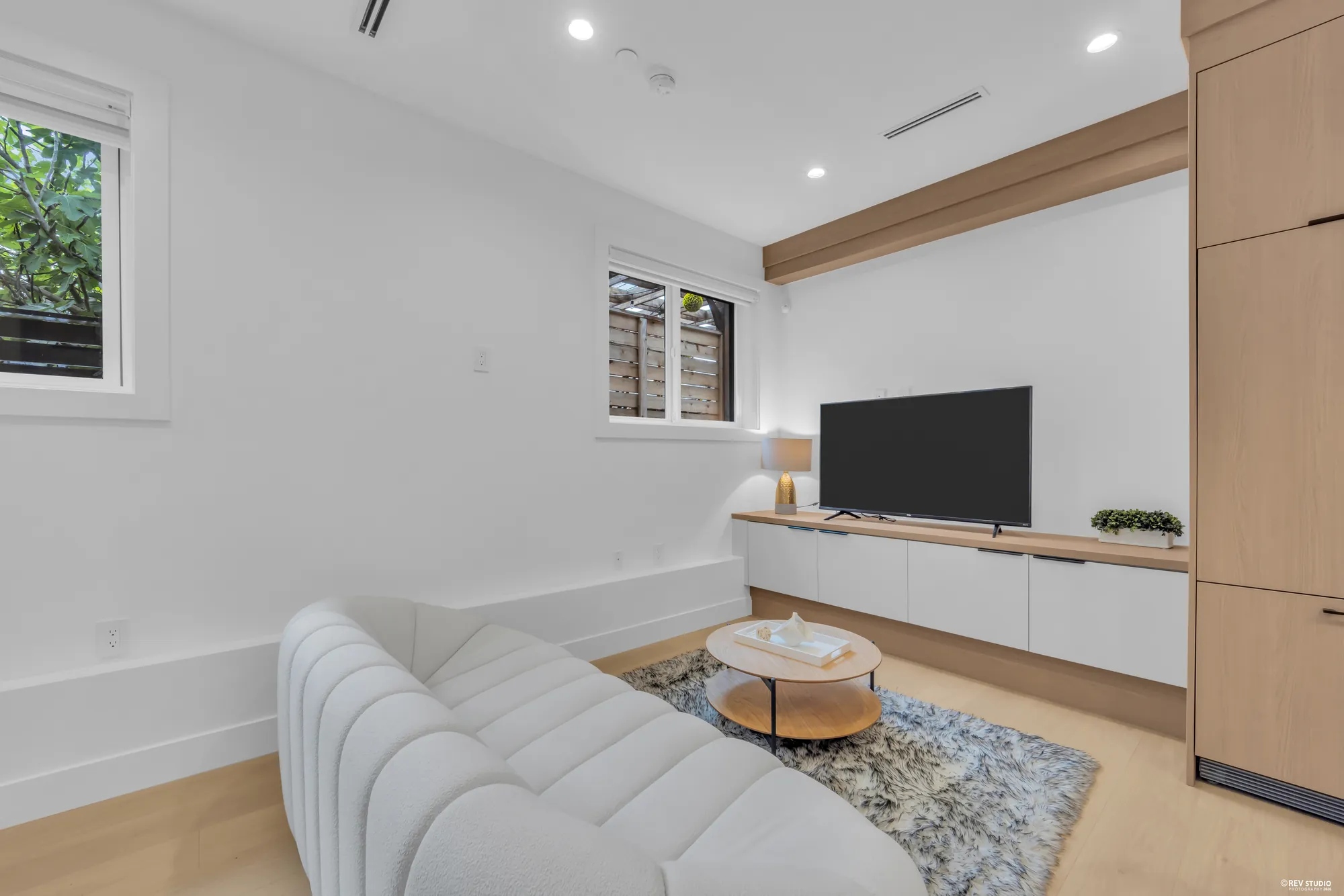 The sitting area with a low media cabinet under two windows