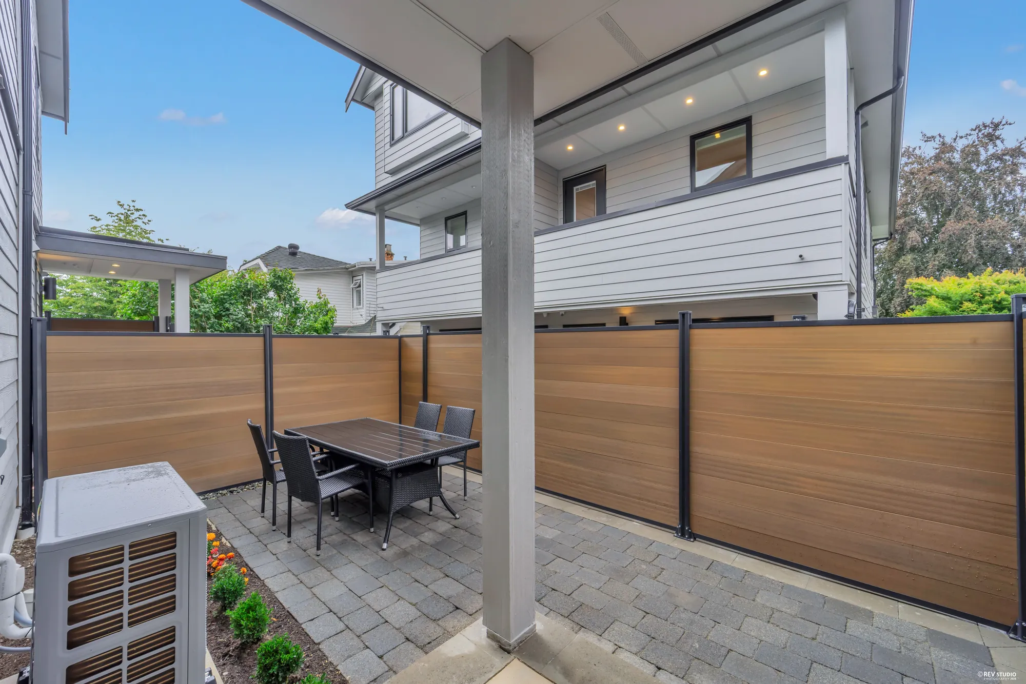 Paved patio with an outdoor dining table and chairs beside the timber fence