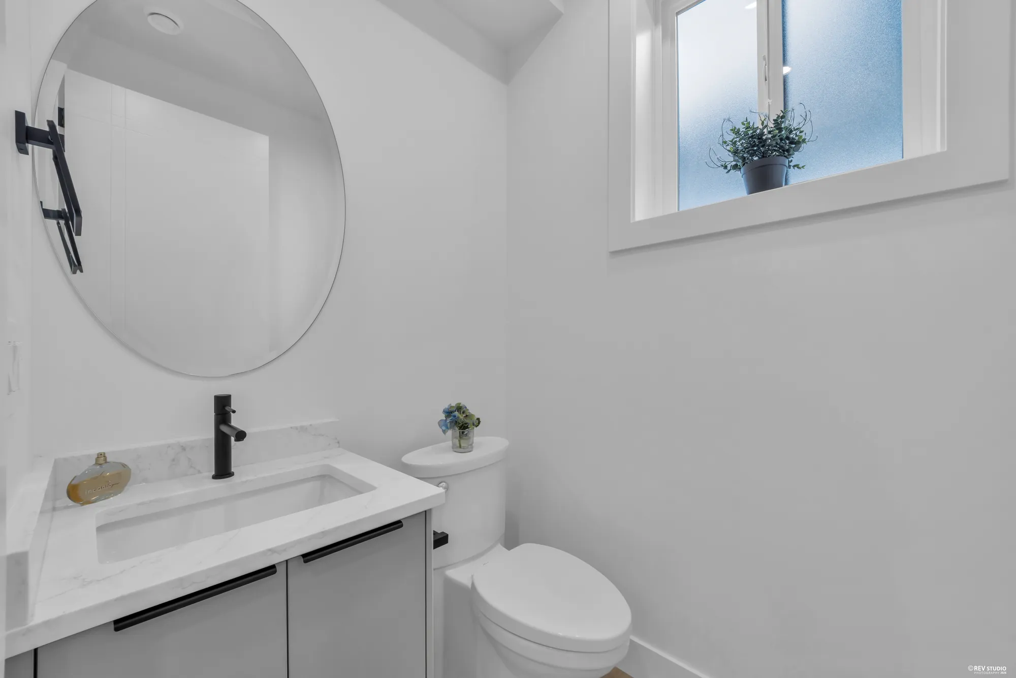 Powder room with a round mirror, stone counter and black tapware