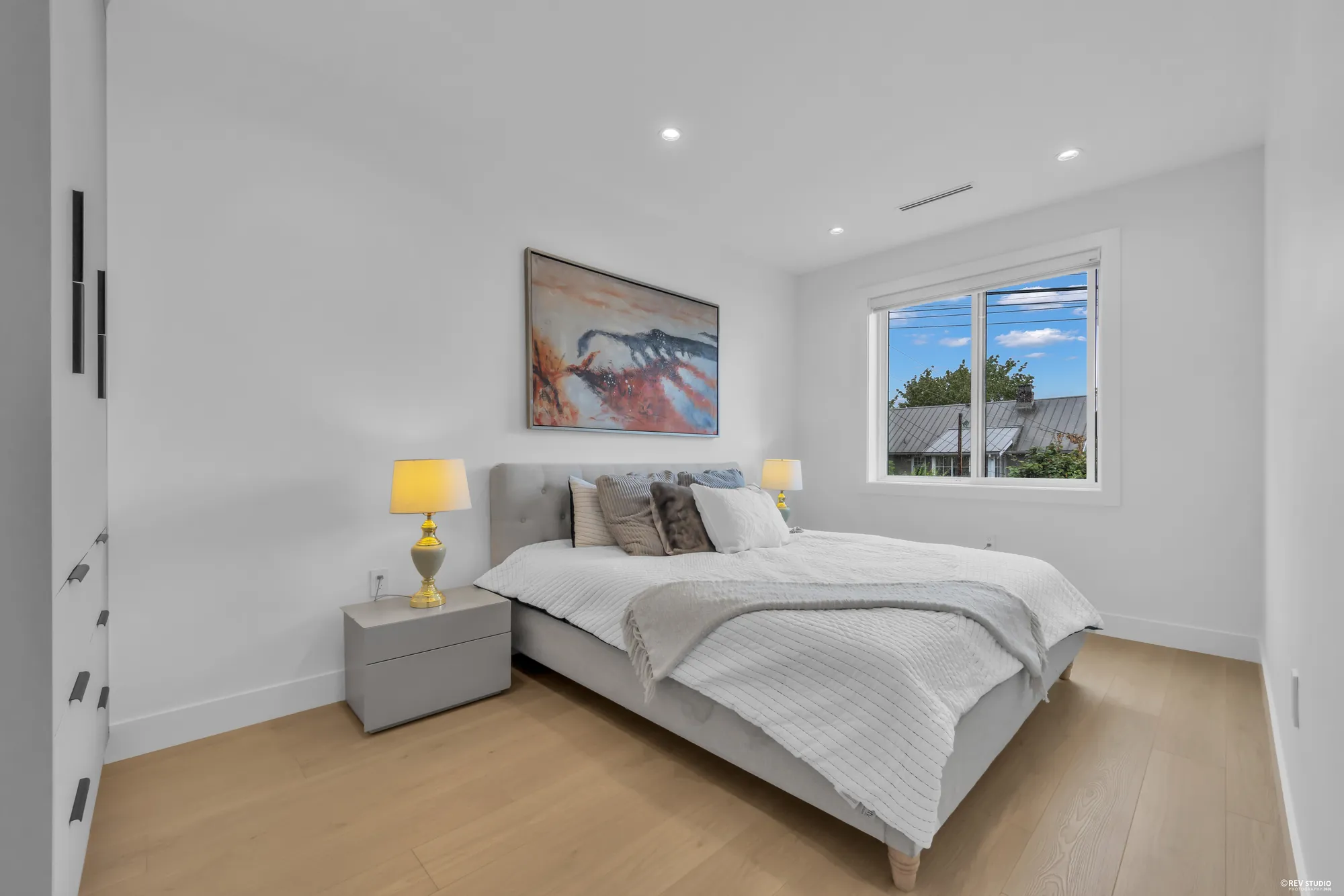 Primary bedroom with a grey upholstered headboard, bedside lamps and a window